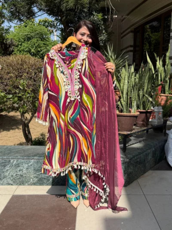 Woman holding a colorful traditional outfit with a hanger outdoors.